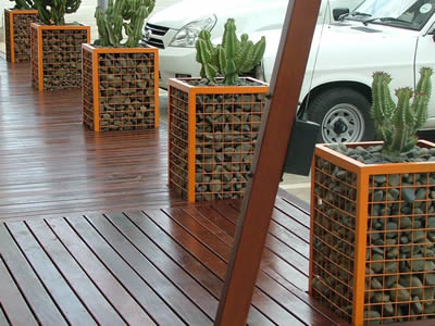Five welded gabion with stones and cactus are places on the street.